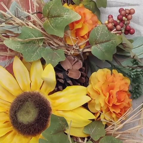 Harvest wreath with sunflowers, orange blooms and pinecones