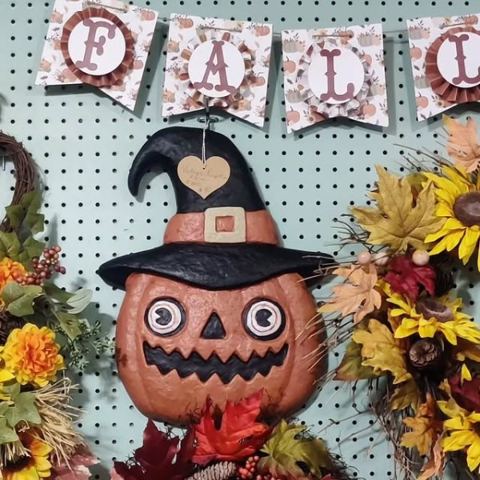 Jack-o-lantern in a witch hat under a FALL banner, with autumn wreaths